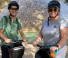 Three smiling people wearing helmets are standing with Segways in front of the Alamo on a sunny day