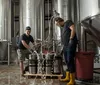 Four women are smiling for a photo in front of wooden barrels possibly at a winery or brewery