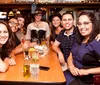 A group of people are posing happily for a photo at a table inside a bar or restaurant