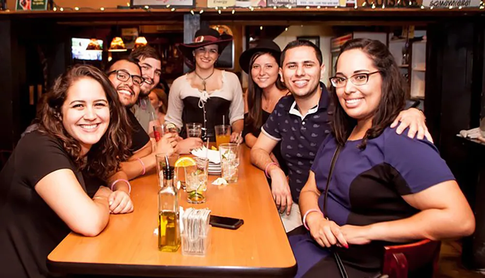 A group of people are posing happily for a photo at a table inside a bar or restaurant