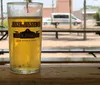 A person is pouring a dark beer from a tap into a branded glass with a foamy head forming on top