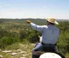 A group of people are horseback riding along a trail through a lush green landscape