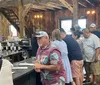 A group of people is gathered inside a rustic-styled building possibly a winery or tasting room with some waiting at the counter and others engaged in conversation