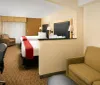The image shows a neatly arranged hotel room with two double beds a work desk armchair and a television set creating a comfortable and functional space for guests
