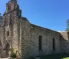 The image shows the historical architecture of an old stone mission with a dome and arches under a clear blue sky