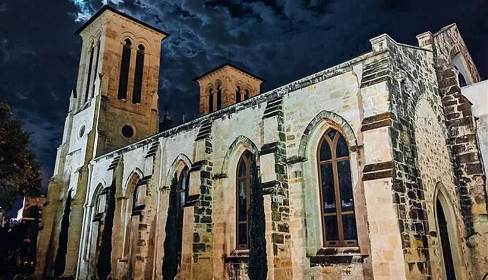 An ancient stone church is illuminated against a dramatic night sky