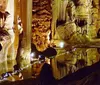 A family is observing the intricate formations inside a beautifully lit cavern