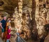 A family is observing the intricate formations inside a beautifully lit cavern