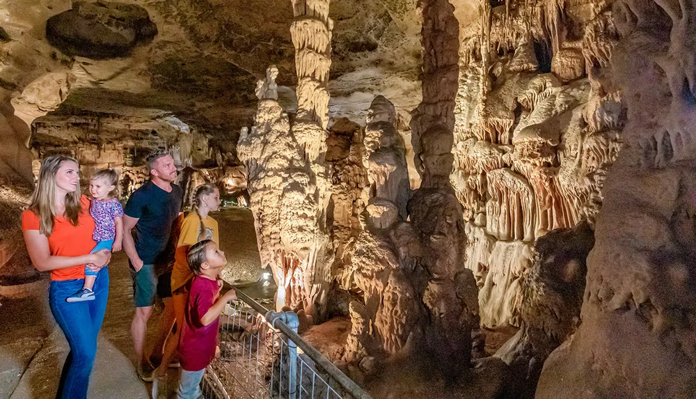 A family is observing the intricate formations inside a beautifully lit cavern
