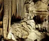 A family is observing the intricate formations inside a beautifully lit cavern