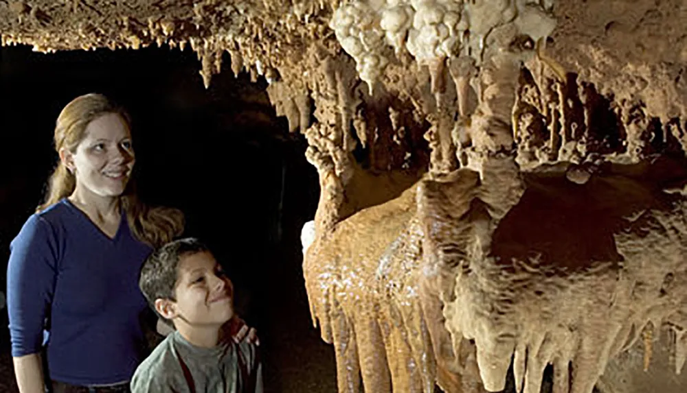 A woman and a boy are admiring the intricate stalactites and stalagmites inside a cave