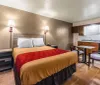 This image shows a compact and functional hotel or motel room with a bed kitchenette dining area and warm lighting