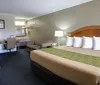 This image shows a neatly arranged hotel room with a king-sized bed a work desk a sofa and a flat-screen TV