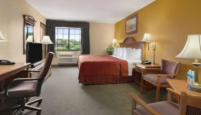 The image shows a standard hotel room with a bed desk chairs and a television depicting a typical accommodation for travelers