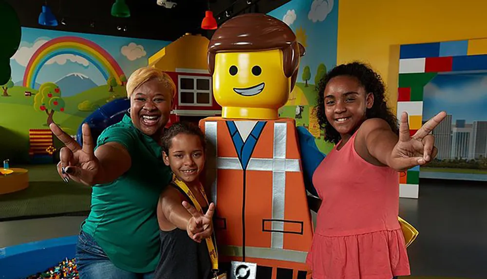 Two people are joyfully posing with a life-sized LEGO figure against a playful backdrop