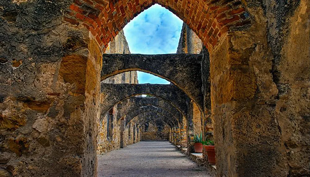 The image shows a series of arches along a weathered corridor in what appears to be an ancient stone structure likely part of historical ruins