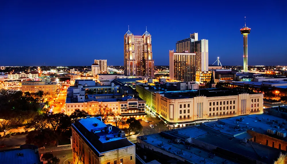 The image showcases a vibrant cityscape at twilight with illuminated buildings and a prominent tower standing tall against the evening sky