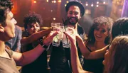 A group of friends are toasting with drinks at a vibrant party.