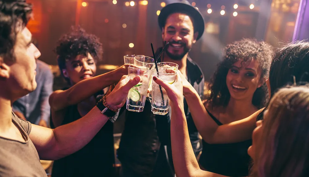 A group of friends are toasting with drinks at a vibrant party