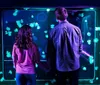 Two people are holding hands while looking at glowing jellyfish in an aquarium