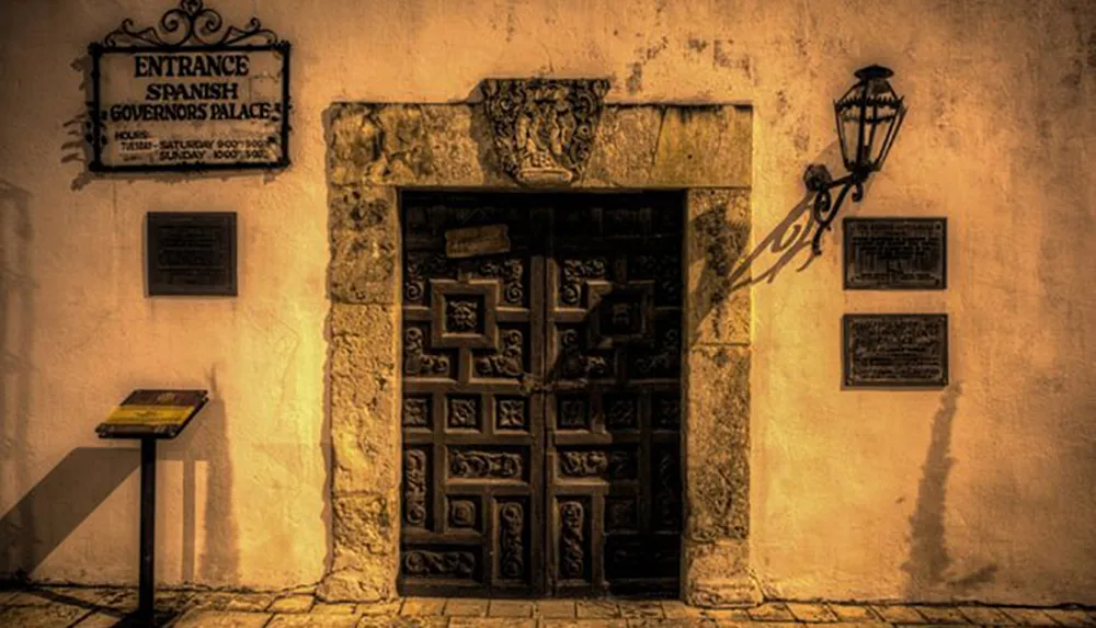 The image shows an ornate entrance door flanked by historical plaques and a lantern labeled as the Spanish Governors Palace evoking an old-world ambiance