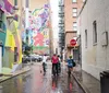 Three cyclists wearing helmets pause for a conversation under an overpass with colorful murals in the background