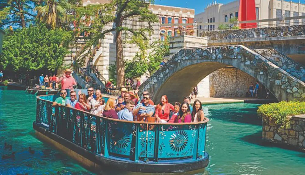A group of people enjoys a boat tour on a picturesque urban river flanked by lush greenery and stone architecture