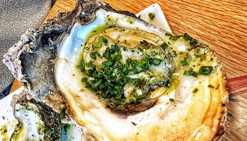 The image shows a large dressed oyster on the half shell garnished with green onions