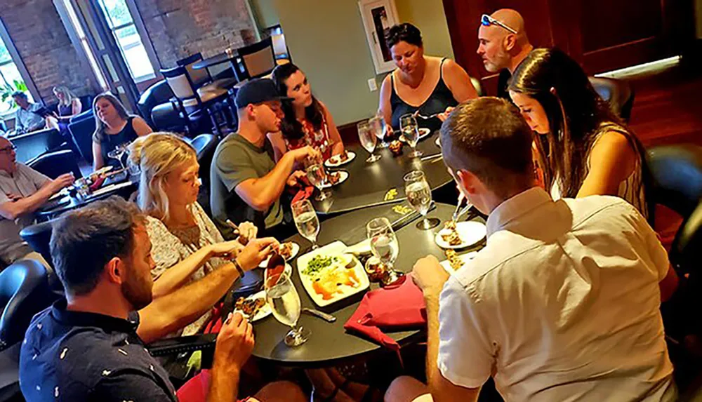 A group of people are enjoying a meal together at a round table in a restaurant