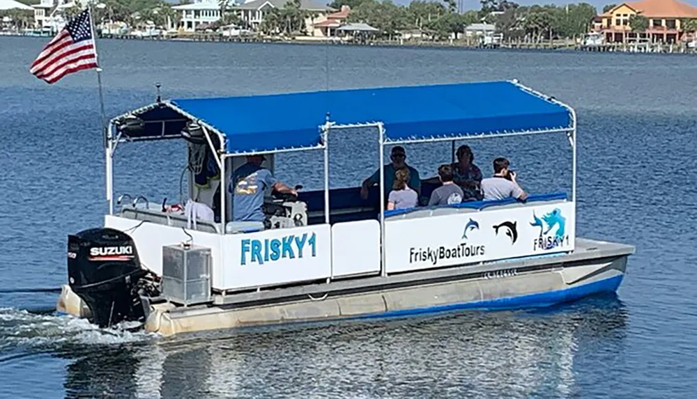 A group of passengers enjoys a boat tour on a pontoon named FRISKY1 with an American flag displayed on the back