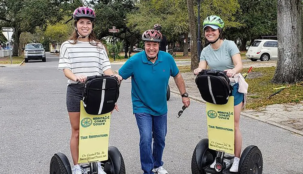 Three people are posing with Segways on a residential street wearing helmets and smiling with the signage indicating they are part of a tour group