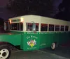 A vintage-style green and white tour bus labeled Go Retro advertises a hop-on hop-off service at night