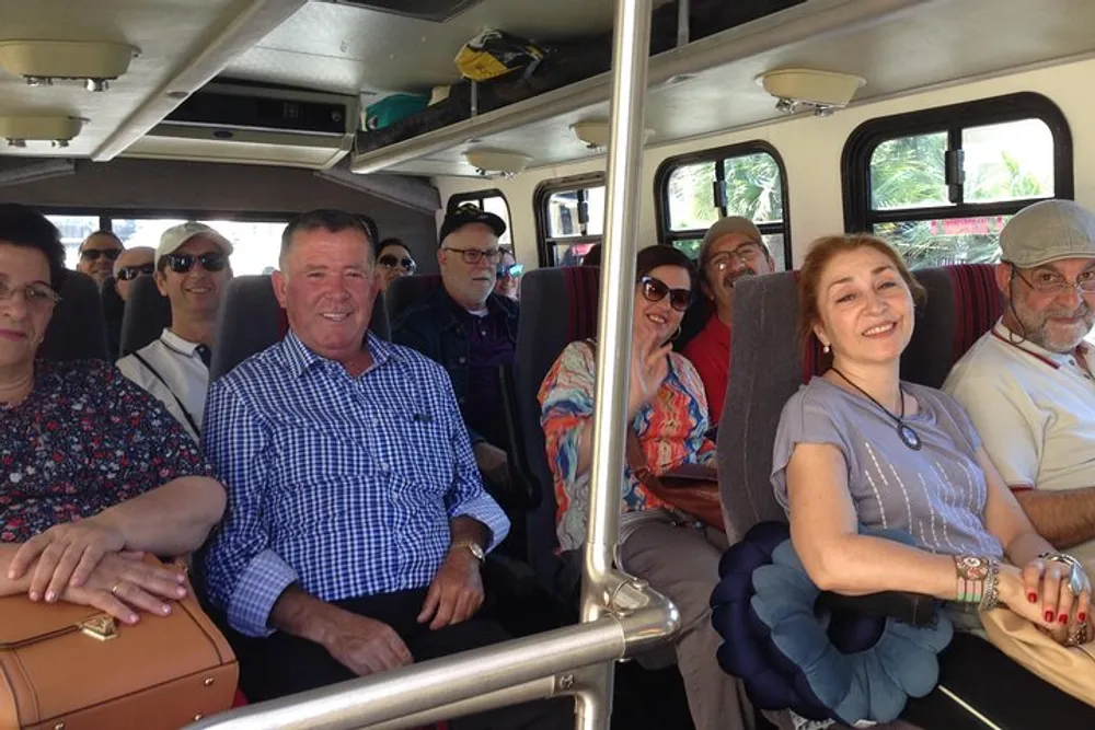 A group of people is sitting inside a vehicle possibly a bus or van smiling and posing for the camera