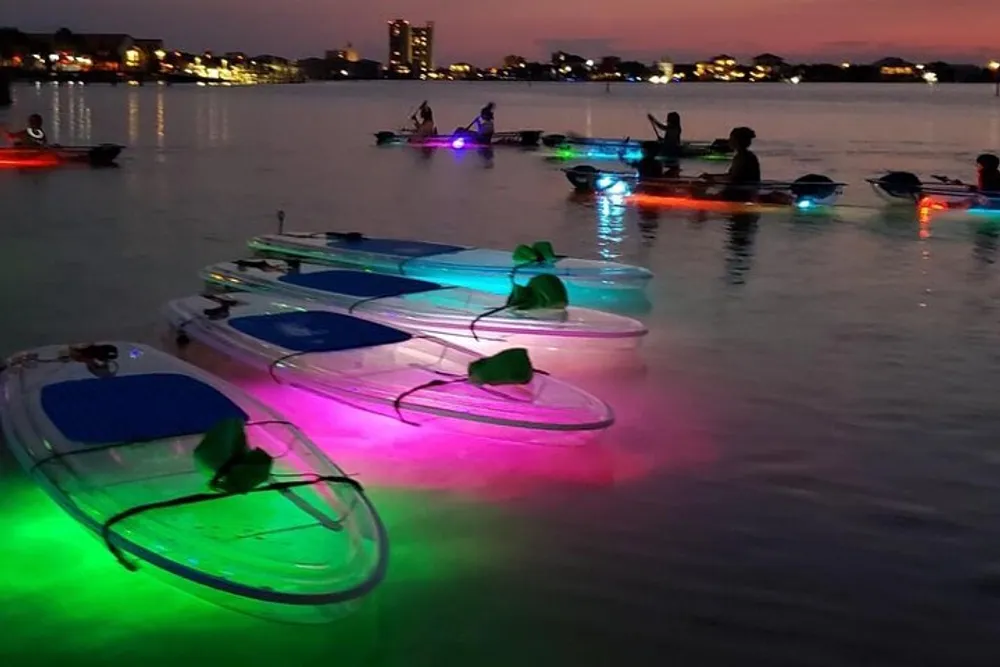A group of people on illuminated paddleboards enjoy the water at dusk