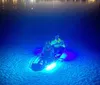 Two people are kayaking at night with underwater lights illuminating the water around them creating a glowing effect