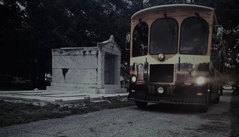 A trolley bus is parked on a road beside what appears to be a cemetery creating a somber atmosphere