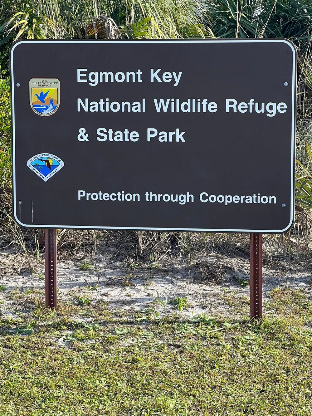 The image shows a sign for Egmont Key National Wildlife Refuge  State Park with a motto Protection through Cooperation and logos of the US Fish  Wildlife Service and Florida Park Service