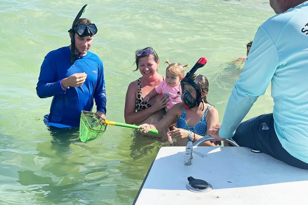 A group of people appears to be engaged in a snorkeling activity with some participants in the water and others on a boat and one individual holding a net with marine life to show the others