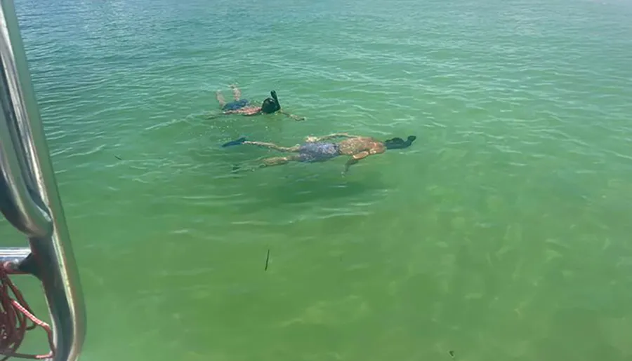 A person is floating on their back in clear greenish water, appearing relaxed and peaceful.