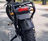 Two fat-tire electric bicycles are parked under a bridge near a body of water