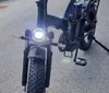 Two fat-tire electric bicycles are parked under a bridge near a body of water