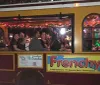 Passengers are enjoying a festive ride in a trolley adorned with twinkling lights looking out at colorful illuminations outside