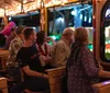 Passengers are enjoying a festive ride in a trolley adorned with twinkling lights looking out at colorful illuminations outside