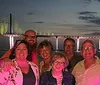 A group of passengers enjoys a sunset cruise near the coast on a pontoon boat with a tranquil ocean backdrop while an inset image shows a brightly lit bridge reflecting on the water at night
