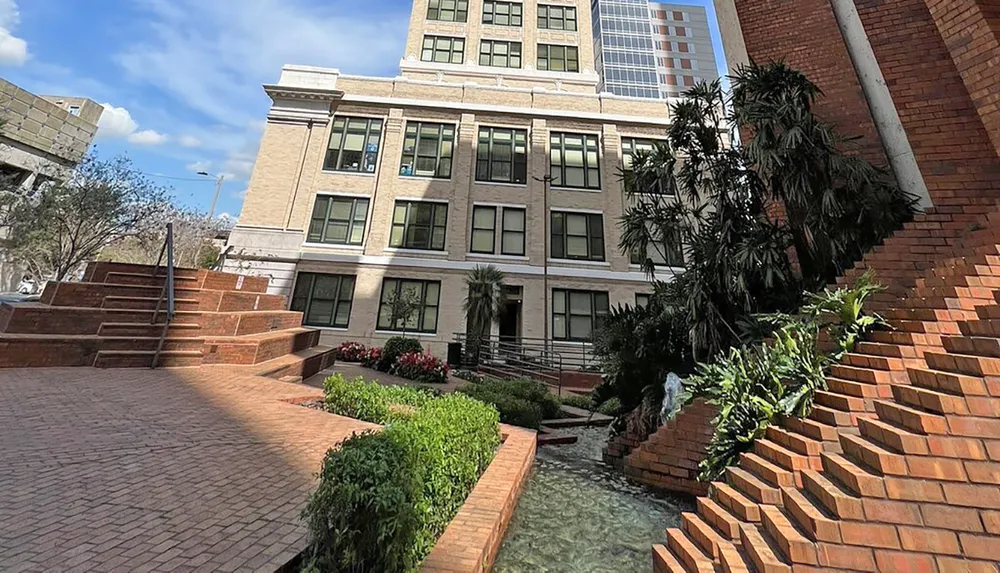 The image features a landscaped urban space with terraced brick steps greenery and a classical building in the background blending natural and architectural elements