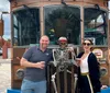 Two people are smiling and posing next to a skeleton figure in front of a trolley-style vehicle that advertises a Mystery Tour Crawl