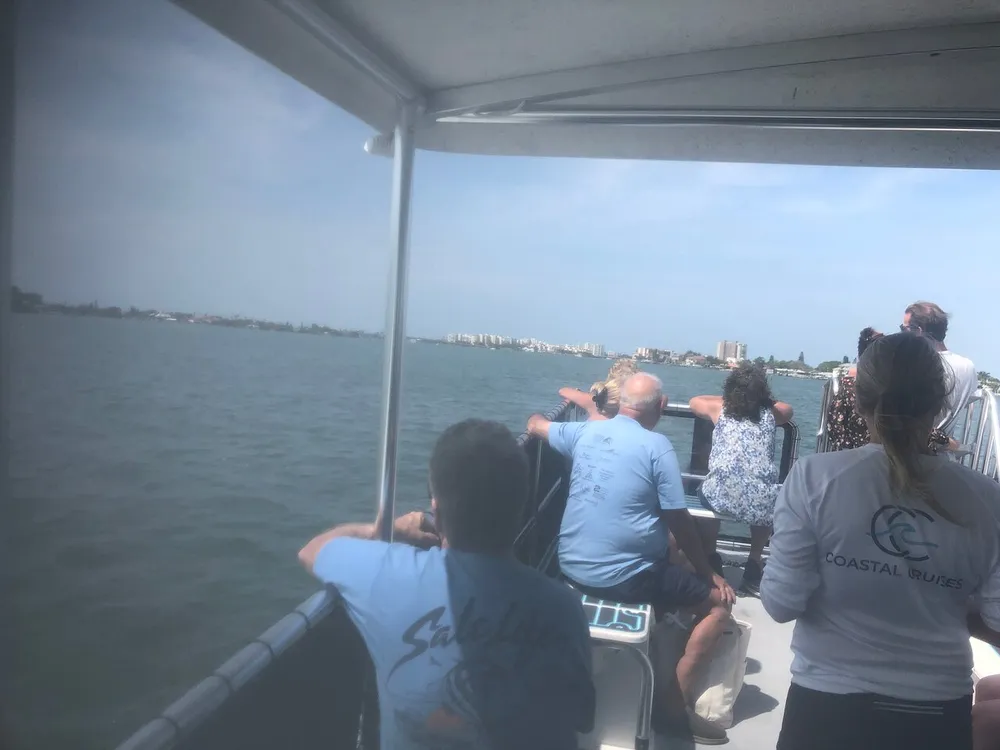 Passengers are enjoying a boat tour with views of a coastal cityscape under a clear sky