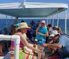 A group of people are enjoying a sunny day on a shelling and dolphin watch tour boat cruising through blue waters