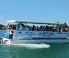 A group of people are enjoying a sunny day on a shelling and dolphin watch tour boat cruising through blue waters