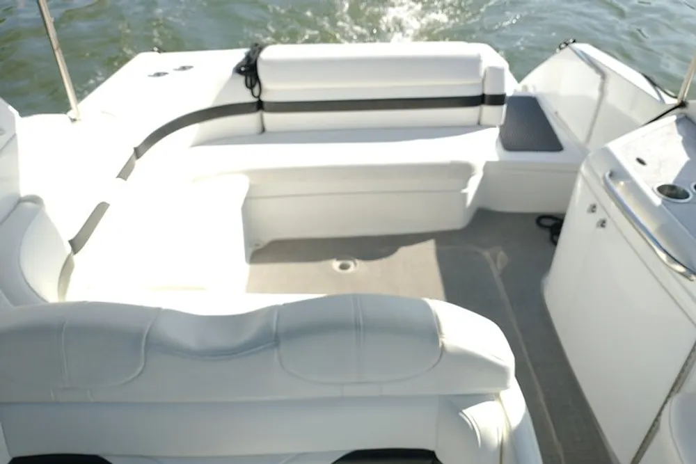 The image shows the interior of a boat with white seating and a view of calm waters in the background captured during a sunny day